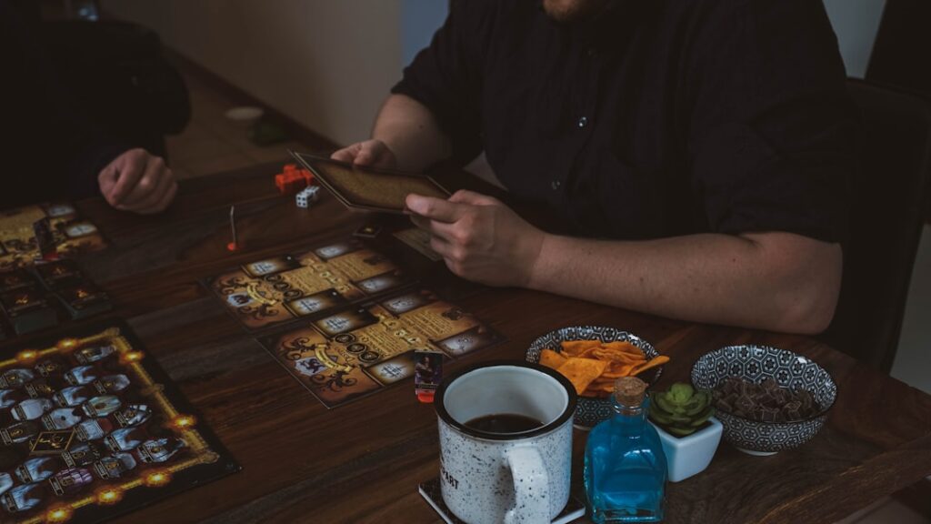 Two players collaborating over a tabletop game with snacks and game pieces