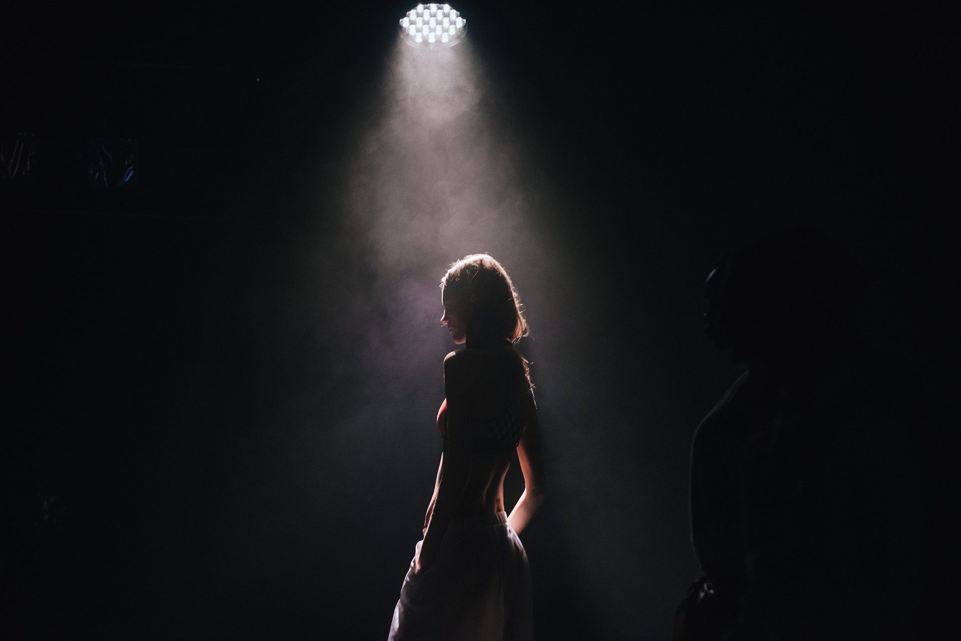 A performer standing alone in a theatrical spotlight